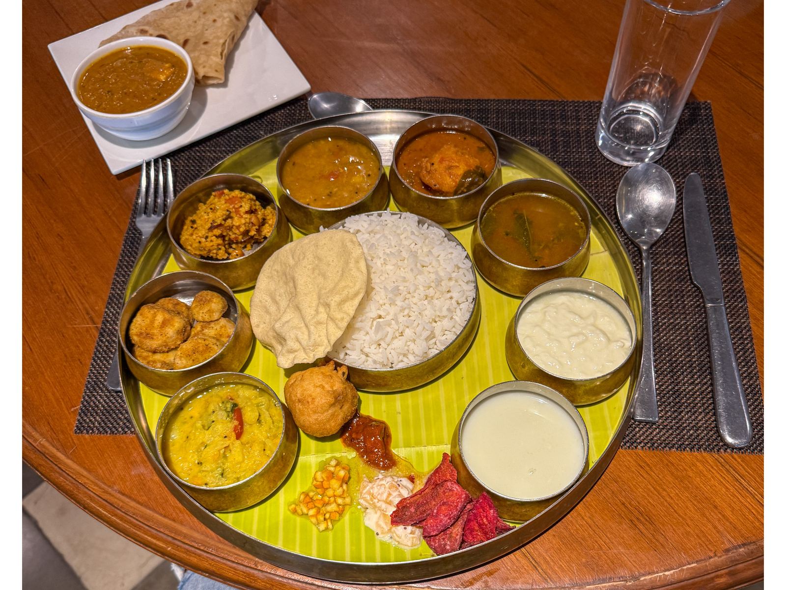 Thali indio con arroz, panes y varios curries servidos en cuencos metalicos