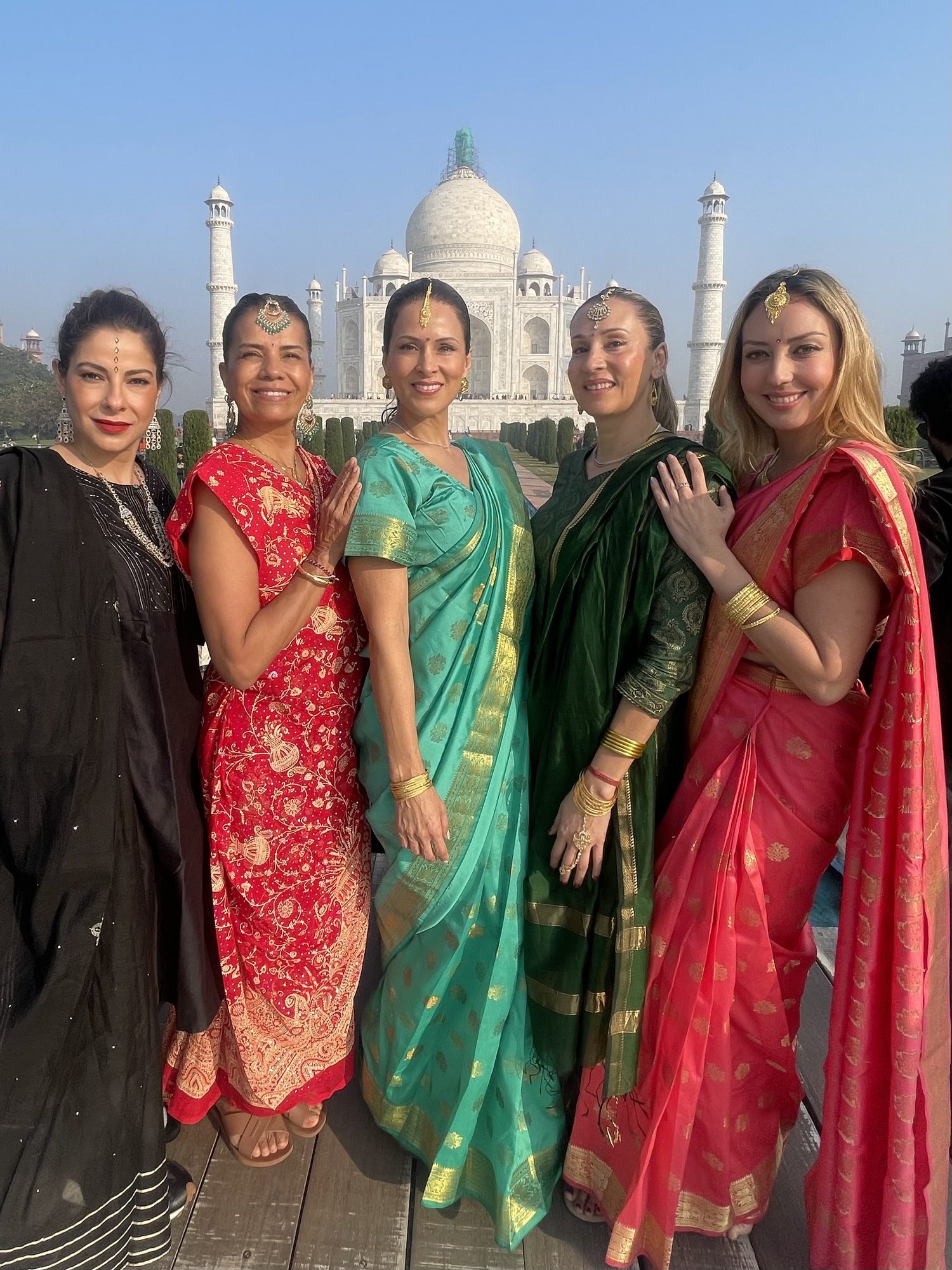 Cinco viajeras latinoamericanas vestidas con saris frente al Taj Mahal en Agra