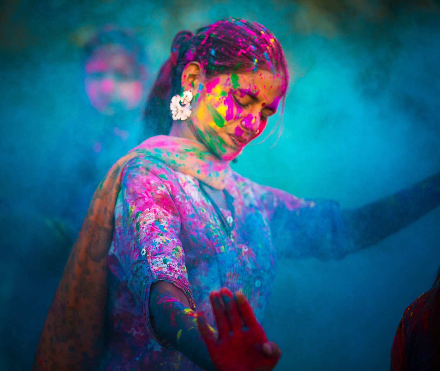 Multitud celebrando un festival de colores en la India, con pigmentos brillantes en el aire y templos al fondo