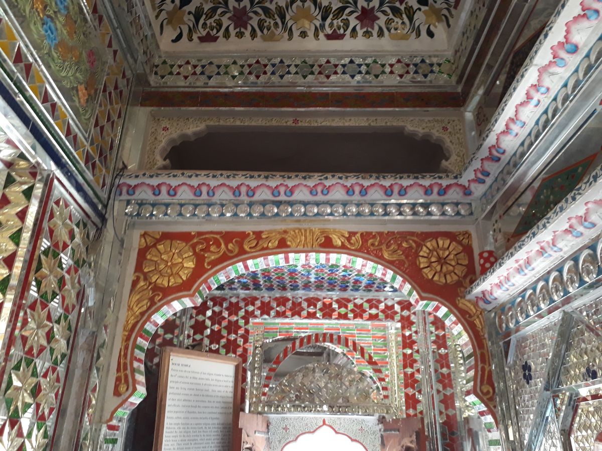 Arco cubierto de espejos, pintura roja y dorada en el templo doméstico de la Patwon ki Haveli, en Jaisalmer