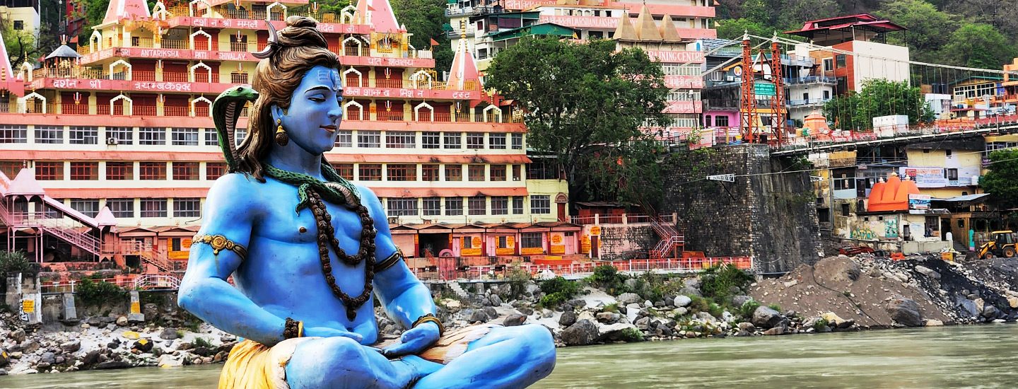 Practicante de yoga al amanecer en un ghat a orillas del río Ganges en Rishikesh, con las estribaciones del Himalaya al fondo