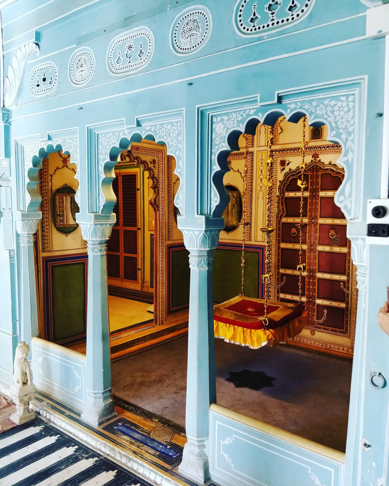Arcos lobulados azules y puertas doradas en una sala del City Palace de Udaipur