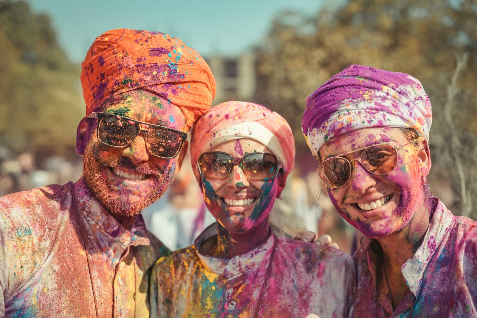 Tres viajeros sonrientes cubiertos de colores en Holi