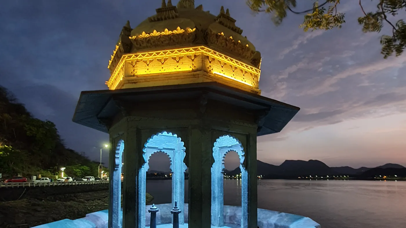 Pabellón de Jag Mandir iluminado al anochecer sobre el lago Pichola
